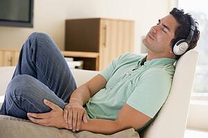 Man in living room listening to headphones sleeping