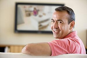 Man in living room watching television smiling
