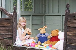 Young girl in shed playing tea and smiling