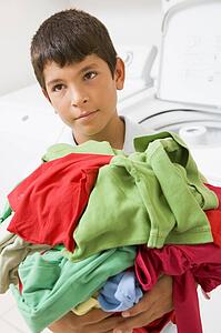 Young Boy Holding A Pile Of Laundry