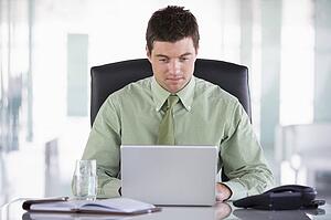 Businessman sitting in office with personal organizer and laptop