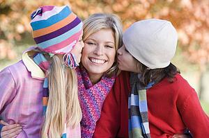 Mother and two young children outdoors in park smiling