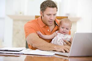 Father and baby in dining room with laptop