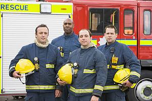 Four firefighters standing by fire engine