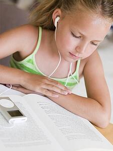 Young Girl Reading A Book While Listening To An MP3 Player