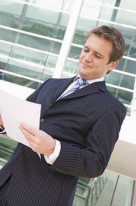 Businessman standing outdoors looking at paperwork