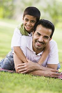 Father and son outdoors in park embracing and smiling (selective focus)