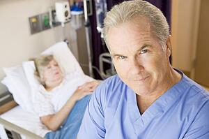 Doctor Standing In Patients Room, Looking Serious