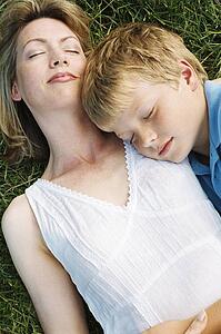 Mother and son lying outdoors sleeping