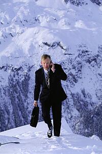 Businessman outdoors on snowy mountain using cellular phone