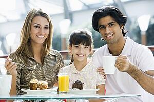 Family at restaurant eating dessert and smiling (selective focus)