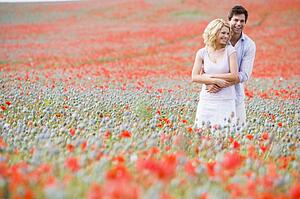 Couple in poppy field embracing and smiling