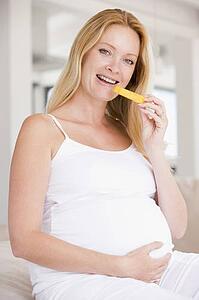 Pregnant woman eating melon slice and smiling