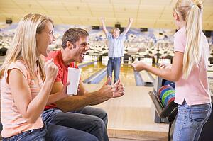 Family in bowling alley cheering and smiling