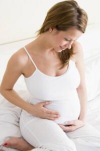 Pregnant woman sitting in bed smiling