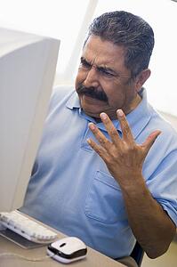 Man at computer looking at monitor frustrated (high key)