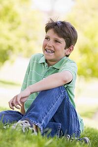 Young boy sitting outdoors smiling