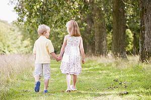 Two young children walking on path holding hands