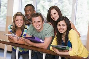Five students in corridor leaning on railing with notebooks
