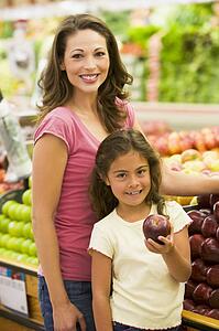 Woman and daughter shopping for apples at a grocery store