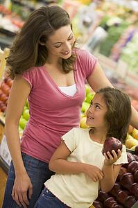 Woman and daughter shopping for apples at a grocery store