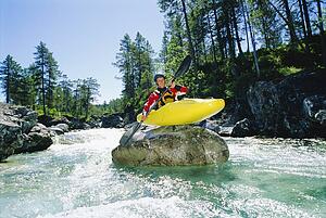 Kayaker on top of rock in rapids smiling