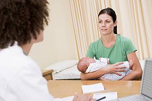Doctor with laptop and woman in doctor's office holding baby