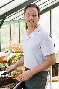Man in greenhouse putting soil in pot