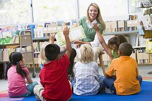 Students in class volunteering for teacher
