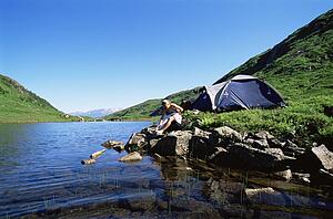Woman at campsite sitting near river