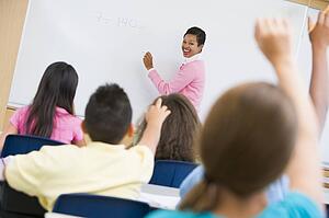 Students in class volunteering for teacher at front board (selective focus)