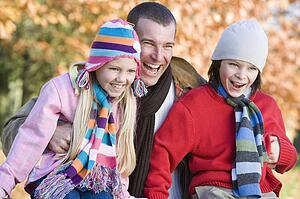 Father and two young children outdoors in park laughing (selective focus)