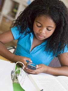 Young Girl Distracted From Her Homework, Playing With A Cellphone