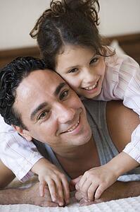 Father and daughter girl relaxing on bed in bedroom smiling (selective focus)