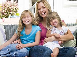 Woman and two young girls sitting on patio smiling