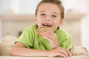 Young boy eating cookie in living room smiling