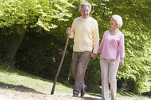 Couple walking on path in park holding hands and smiling