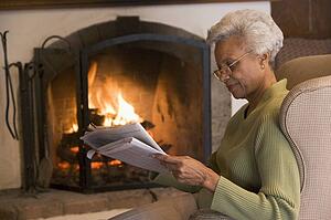 Woman in living room reading newspaper