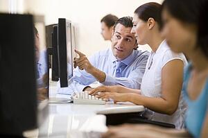 Man assisting woman in computer room