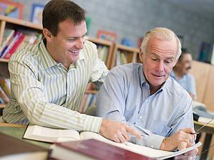 Two men in library talking (selective focus)