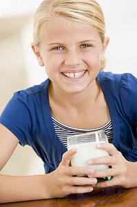 Young girl indoors drinking milk smiling