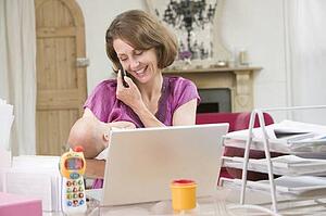 Mother and baby in home office with laptop and telephone