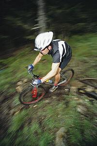 Man outdoors on trails riding bicycle (selective focus)