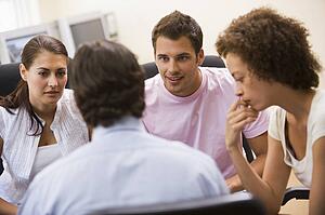 Man giving lecture to three people in computer room