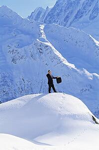 Businessman outdoors on snowy mountain using cellular phone