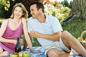 Couple sitting outdoors with picnic smiling