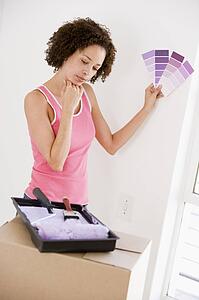 Woman with paint swatches in new home thinking