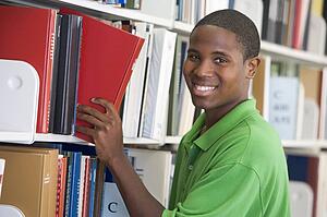 Man in library pulling book off a shelf (depth of field)