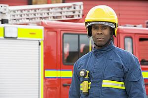 Fireman standing by fire engine wearing helmet