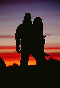 Snowboarder standing outdoors at dusk (silhouette)